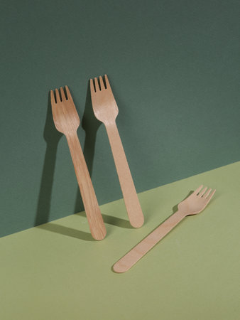 Minimalist eco still life. Wooden forks set on a green two tone background with shadow. creative composition. food and drinkの写真素材