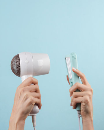 hair style. Hairdryer with an iron in female hands on a blue background. beauty and fashionの写真素材