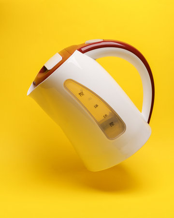 Electric kettle levitates on yellow background with shadowの写真素材