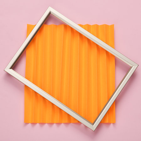 Minimal still life of a golden frame on a colored corrugated backgroundの写真素材