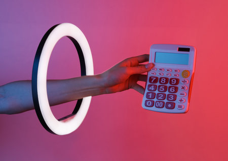 Woman's hand holds calculator through led ring lamp in red blue neon gradient light. creative ideas.の写真素材