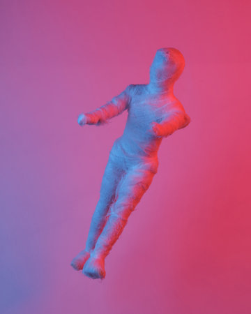 Mummy doll floating in the air, isolated in blue-red neon gradient light. levitating objects. Minimal Halloween conceptの写真素材