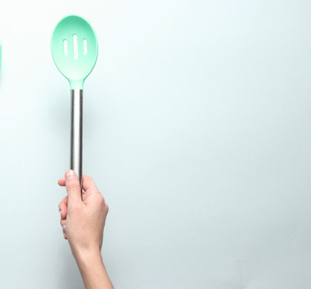 Hand holding silicone shpatula for cooking with metal handle on a gray background. top view.の写真素材