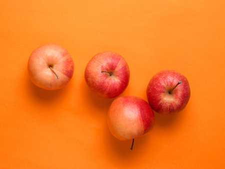 Red apples on orange background. autumn still life. top view.の写真素材