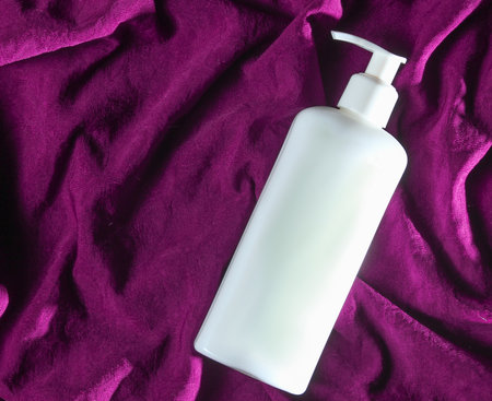White bottle of hand cream on purple background. top viewの写真素材