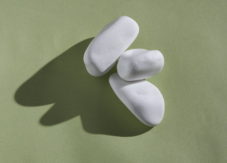 Creative layout with stack of pebbles. Bright green background with shadow. visual trend. Harmony...