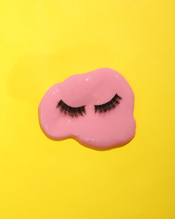 Creative layout with false eyelashes and slime. Bright yellow background. visual beauty trend....