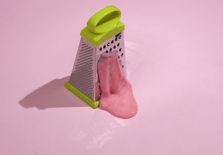 Grater with slime on pink pastel background with shadow. Minimal cooking concept. creative layout