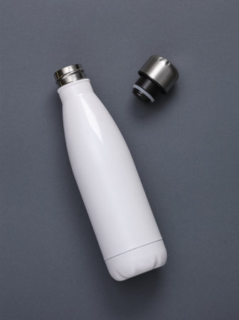 White metal thermal bottle for water on gray background. Stainless Steel Vacuum Insulated Thermos...