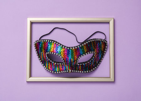 Carnival Venetian mask in a golden frame on pastel background