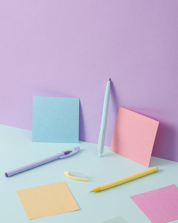Modern and creative composition with multicolored pens and memo papers on a two tone pastel...