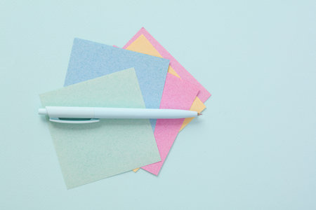 Pen with leaves of memo pieces of paper on blue background. business concept