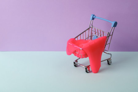 Creative layout, Shopping trolley with neon slime on two tone pastel background. visual trend. Minimalistic aesthetic still life. fresh ideasの写真素材