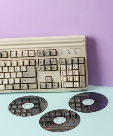 Creative retro 80s layout with old keyboard and cd discs on pastel background. concept pop. Minimal...