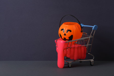 Creative halloween layout, shopping trolley with neon slime and bucket pumpkin on two tone dark background. visual trend. Trick or treatの写真素材