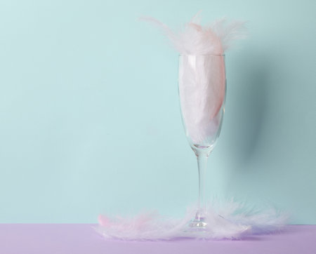 Minimalistic aesthetic still life. Glass with feathers on a pastel two tone background. party conceptの写真素材