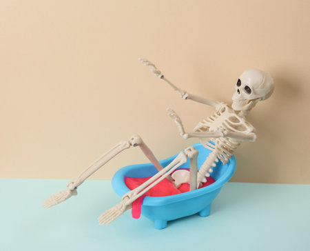 Creative halloween still life, toy bathroom sink with skeleton and neon slime on two tone pastel...