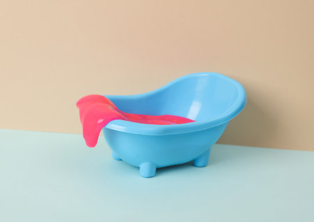Creative layout, toy bathroom sink with neon slime on two tone pastel background. visual trend.