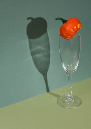 Creative halloween layout, cocktail glass with pumpkin on two tone green background. visual trend....
