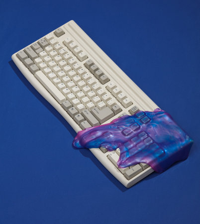 Creative retro layout, Old keyboard with space color slime on dark blue background with shadow....