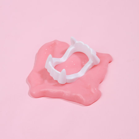 Creative Halloween layout, vampire jaw with slime on pink background with shadow. visual trend....