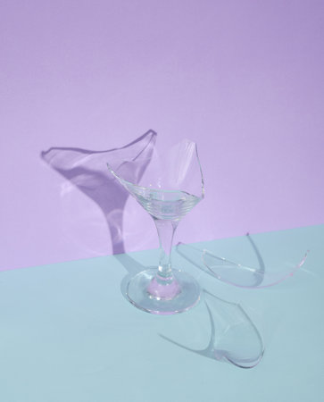 Creative layout with broken cocktail glass on two tone pastel background. Visual summer trend....