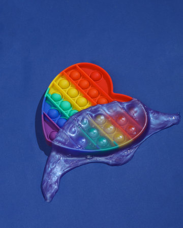 Creative beauty layout, Popping antistress toy with slime on dark bue background with shadow. visual...