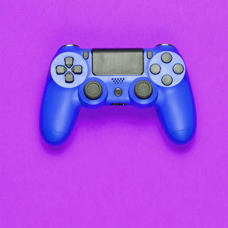Modern blue gamepad (joystick) on purple background. top view