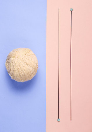 Knitting needles, skeins of wool on a pink-blue pastel background. top view. minimalism