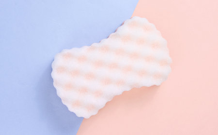 Abrasive sponge on a pink-blue pastel background. top viewの写真素材