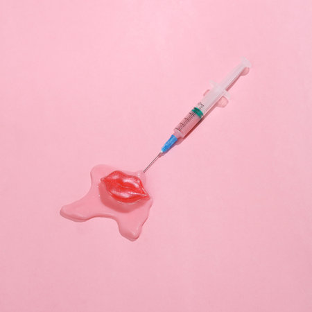 creative layout. Syringe with lips and slime on a pink background. beauty concept. Conceptual popの写真素材