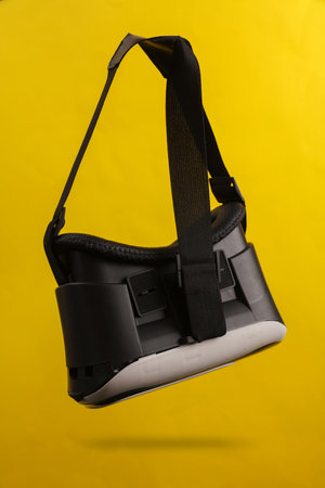 Virtual reality helmet levitating on yellow background with shadow