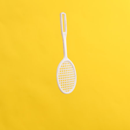 Toy tennis racket isolated on yellow backgroundの写真素材