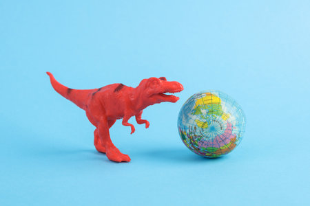 Toy red dinosaur tyrannosaurus rex with globe on blue background. minimalism creative layoutの写真素材