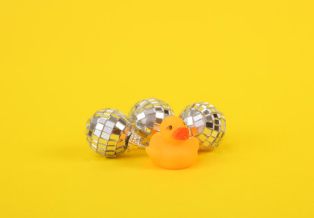 Rubber little ducklings with disco ball on a yellow background. party concept