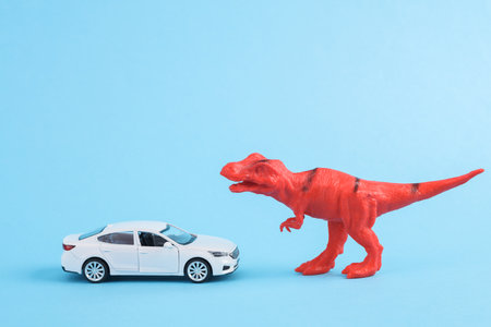 Toy red dinosaur tyrannosaurus rex with car on blue background. minimalism creative layoutの写真素材