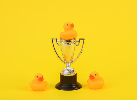 Rubber little ducklings with winner cup on a yellow background