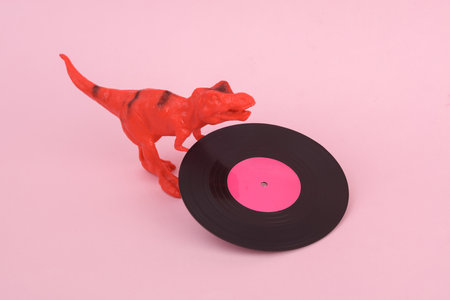 Toy dinosaur tyrannosaurus rex with vinyl plate on pink background. minimalism creative layoutの写真素材