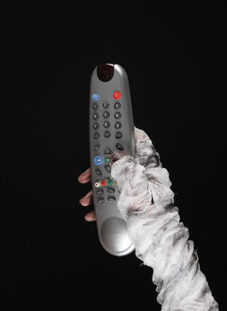 Mummy hand holding tv remorte isolated on black background. halloween conceptの写真素材