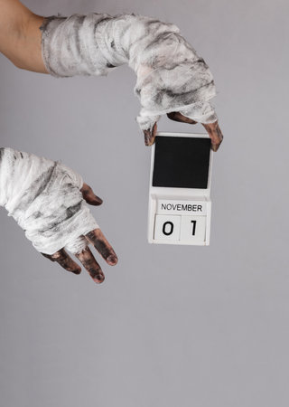 Mummy's hand wrapped in bandage holds 01 november calendar isolated on black background. halloween conceptの写真素材