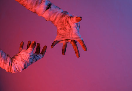 Mummy hands wrapped in a bandage in neon gradient light. halloween concept
