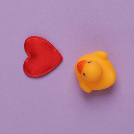 Rubber duck with heart on purple background. top viewの写真素材