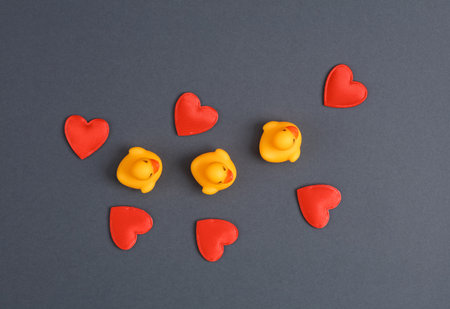 Rubber ducks with hearts on gray background. top viewの写真素材
