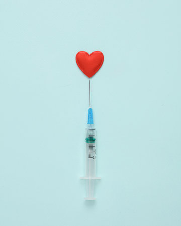 Syringe with a heart on a blue background. love concept. minimal layoutの写真素材