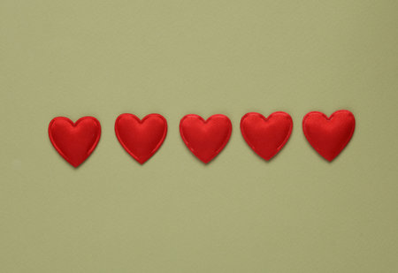 Five red hearts on a green backgroundの写真素材