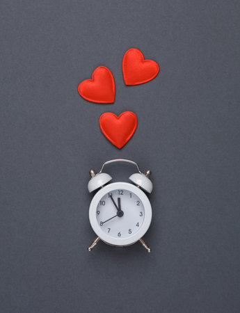 Alarm clock with hearts on gray background. Valentine's Day