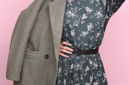 Partial view of woman in stylish coat with floral print on pink background