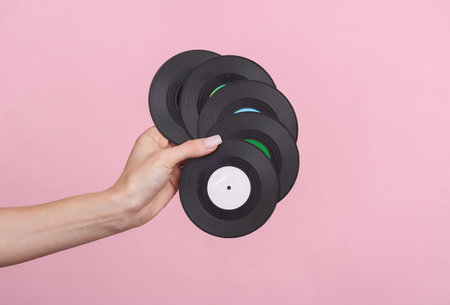 Woman's hand holds a miniature vinyl records on pink background. music conceptの写真素材