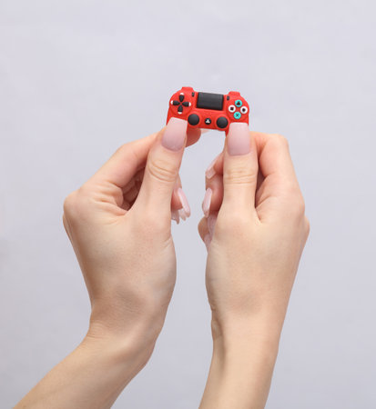 Female hands holding a mini gamepad on a gray background