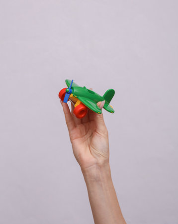 Hand holds a toy plane on gray background. travel conceptの写真素材
